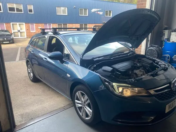 A blue Vauxhall Astra estate at the Attwood Motors workshop door with its bonnet up, the unit next door behind it